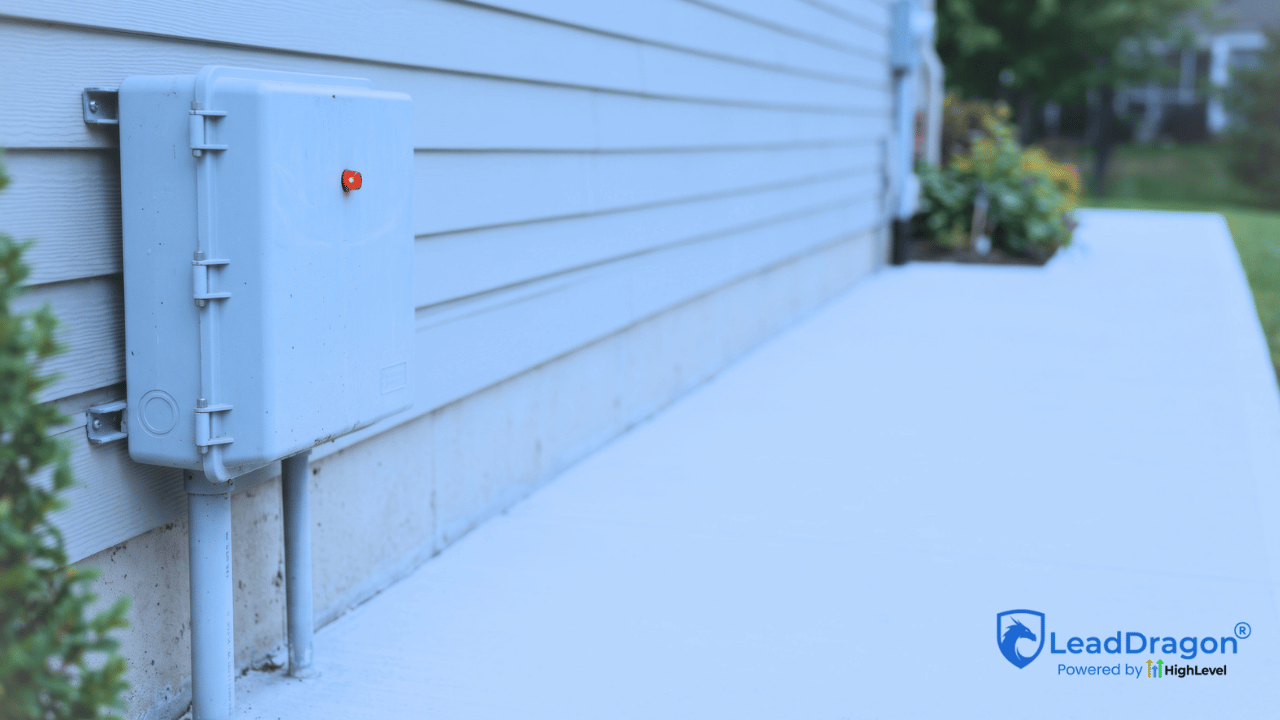 Septic alarm control panel with a warning light active outside a residential property during early evening.