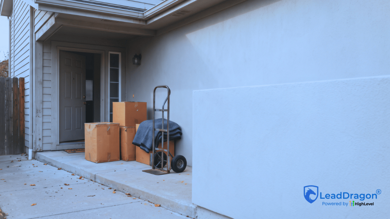 Moving boxes and a furniture dolly beside the entrance of a suburban home.